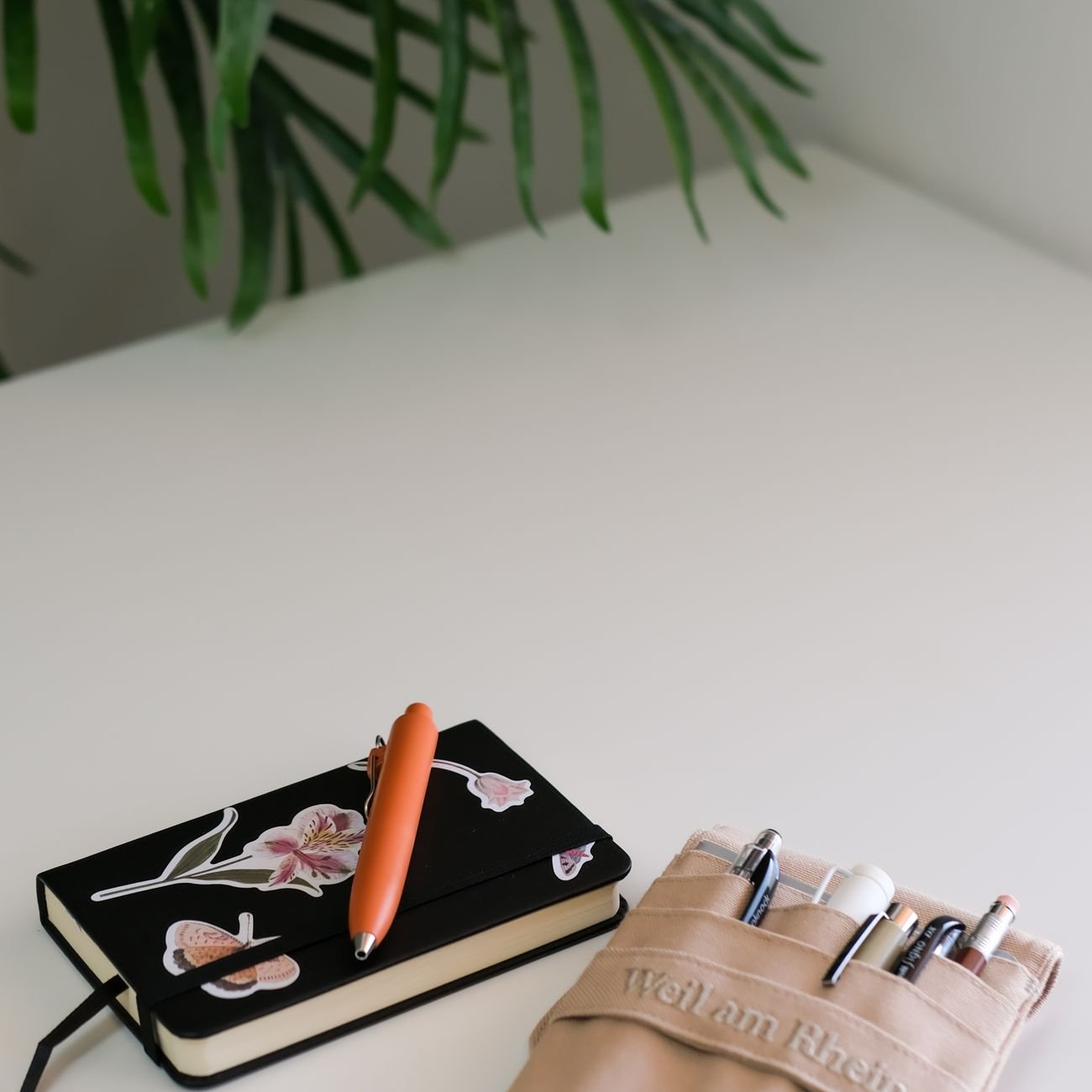 Clean minimalist workspace with decorated notebook and pen holder