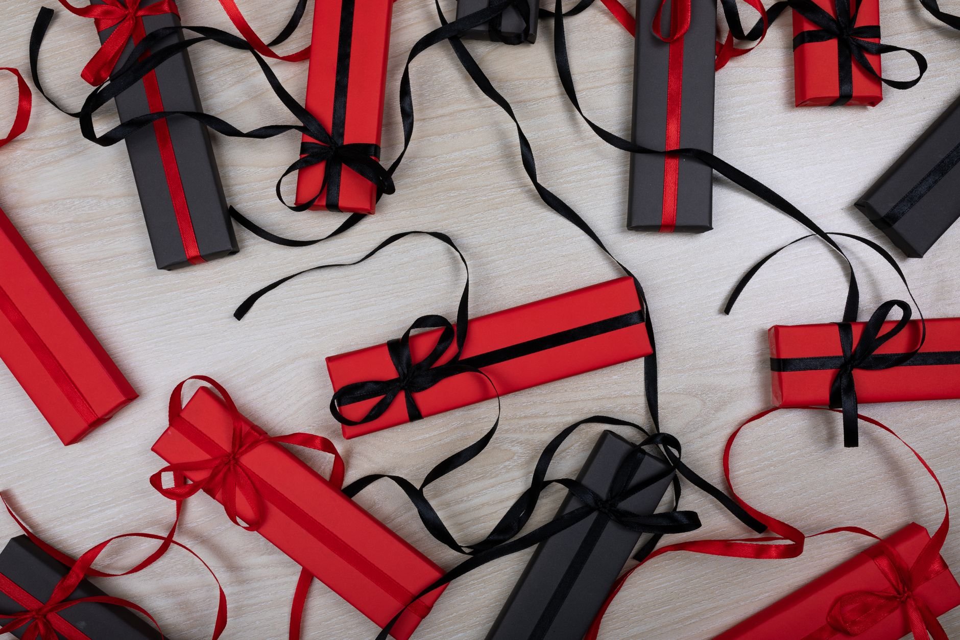 An artistic flat lay of red and black gift boxes with ribbons on a wooden tabletop
